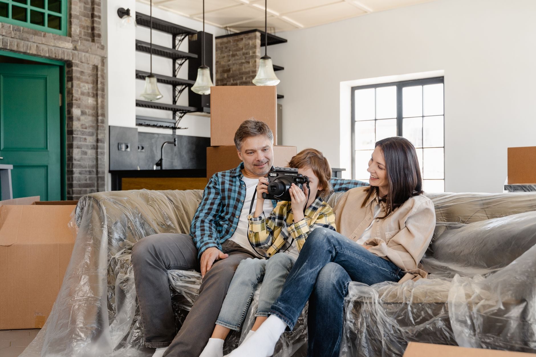 A family sits together on a couch in their new home, embracing the moving experience.